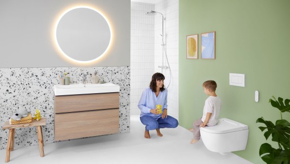 Frau und Kind in einem farbenfrohen Badezimmer mit Geberit Option Spiegel und Geberit AquaClean Alba